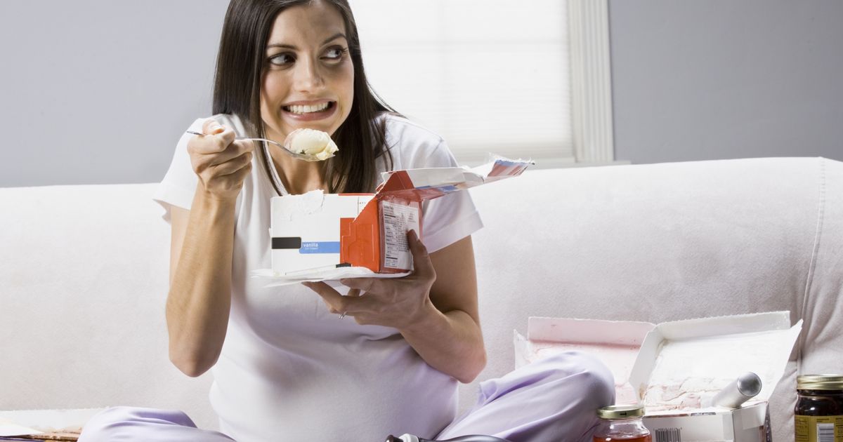Pregnant-woman-sitting-on-a-couch-and-eating-ice-cream